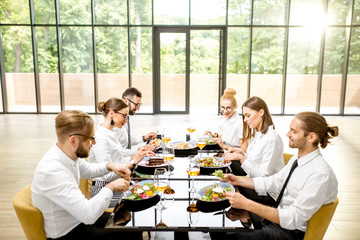 Business people dressed in white shirts sitting together during a business lunch with delicious meals and wine in the modern restaurant