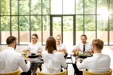 Business people dressed in white shirts sitting together during a business lunch with delicious meals and wine in the modern restaurant
