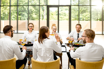Business people dressed in white shirts sitting together during a business lunch with delicious meals and wine in the modern restaurant
