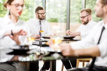 Business people having lunch with delicious meals sitting in pairs at the modern restaurant