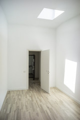 Attic room interior/Empty white room with attic window on the ceiling and wooden floorboards.