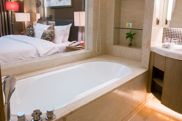 White ceramic bathroom and bathtub with bath set beside white bedroom 