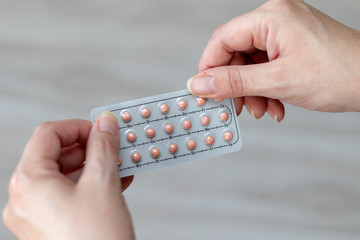 Full package of pink birth control pills in the hands of a woman