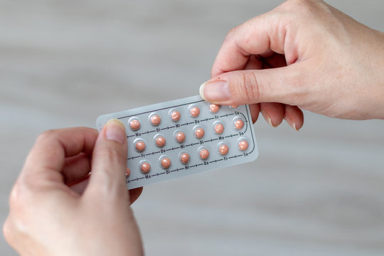Full package of pink birth control pills in the hands of a woman