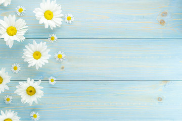 White daisies and garden flowers on a light blue worn wooden table. The flowers are arranged side, empty space left on the other side. - 210361112