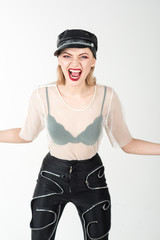Trendy girl in rock style. Girl in leather cap and pants. Cool look of sexy girl with fashionable makeup. Rock woman with blonde hair on white background. Fashion model with stylish hairdo.