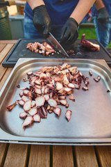 Hand cook using knife cutting squid slices on stove