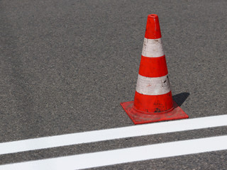 The cross-decorated pedestrian crossing with the still not dried out red. Restriction of traffic by road signs. Update road pedestrian markings. Luminescent paint on gray asphalt. Men at work.