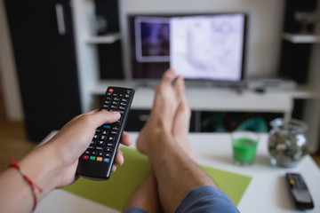 Man's leg on the table. Man with TV remote control. Man in the apartment. Live your dream.