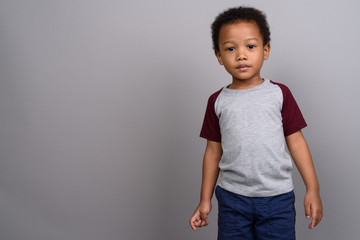 Young cute African boy against gray background