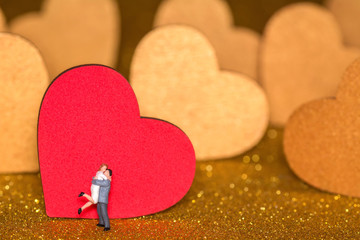 Miniature people and golden hearts. A loving couple on a radiant background
