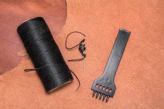 Natural leather, tool for creating products and bobbins of wax yarns. View from above.