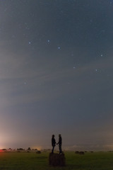Young girl and boy staying on the haystack and watching the stars in the sky. Romantic