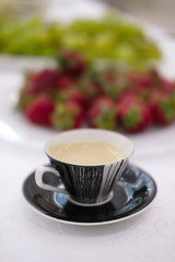 Soft focus photo of cup of coffee with fruits on background
