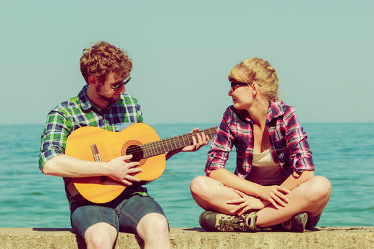 Young man playing guitar to his girlfriend outdoor