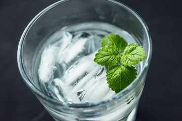 Cocktail wather with ice and mint in a glass on black background. Summer refreshing drink.