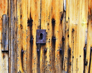Detail of old door, with yellow paint and rusty lock
