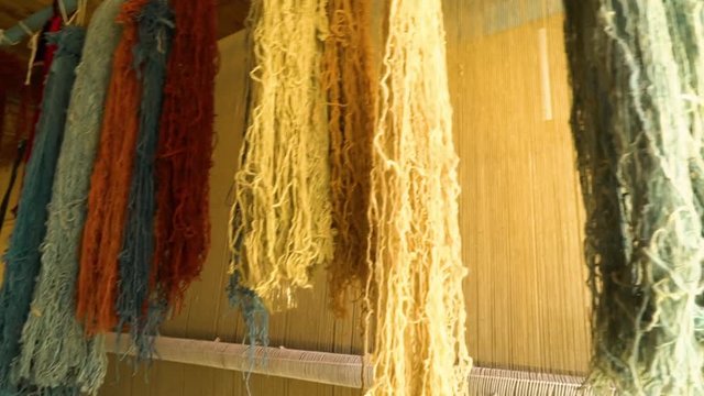 A moving shot of fibers and strings hanged inside a rug factory.
