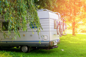 White trailer attached to the bike stands in a clearing in the woods on a Sunny day