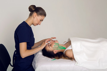 Obraz premium female cosmetician doing the taping of the face of the patient