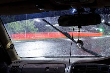 beautiful drops of water on the windshield of the car with the glass cleaners turned on, during a thunderstorm and rain in the night city. front and back background blurred