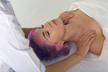 Fototapeta na wymiar massage therapist cosmetologist doing massage of the shoulders, the girl lying
