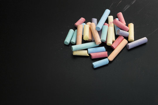 Group of multicolored chalks on black chalkboard