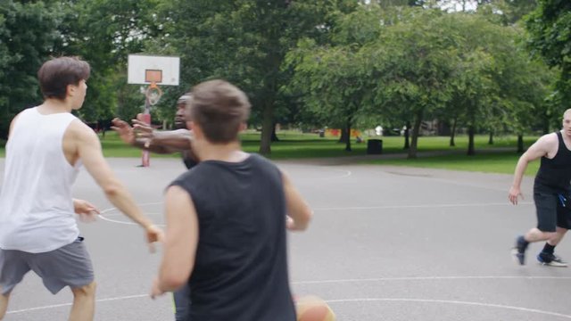 Basketball players playing as one player breaks free for a dunk, in slow motion
