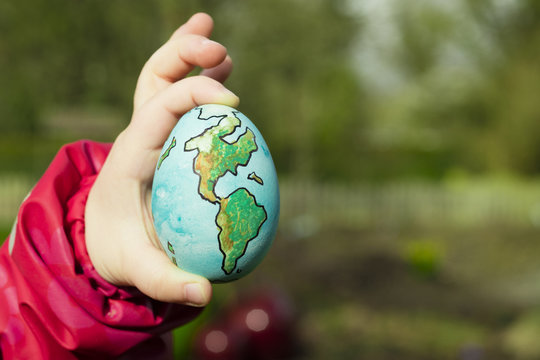Child holding a painted egg  with shape of Planet Earth 