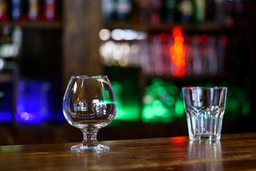 Two empty glasses on the bar. Blurred colored background