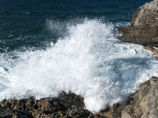 Ola salpicando en las rocas de la costa litoral