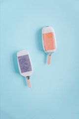 Ice-cream, popsicles wrapped in silver aluminium foil from above on a round plate. Pastel blue background. Minimalism food photography. Copyspace