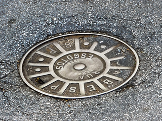 Sao Paulo, Brazil, June 08, 2018. Top-down of a worn steel manhole cover on the cracked concrete streets of Sao Paulo, Brazil