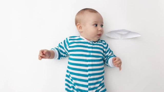 Adorable baby plays with paper boat, top down view