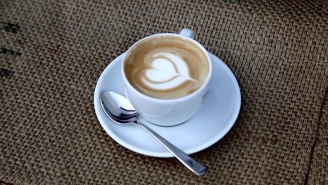 Cappuccino auf Leinen Kaffeesack, Video footage, Tasse wird von unscharf auf scharf gestellt, 1080p Full HD