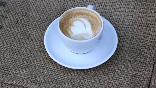Cappuccino auf Leinensack, Hand rührt den Milchschaum um, Full HD 1080p footage 25 fps