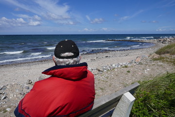 Einsamer Alter Mann sitzt auf einer Bank am Meer