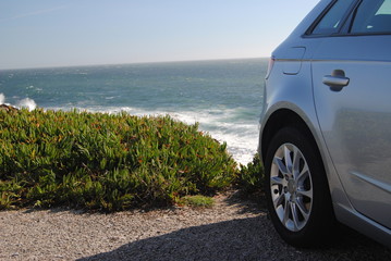 Fototapeta na wymiar Carro cinzento prata estacionado à beira mar numa zona de falésia