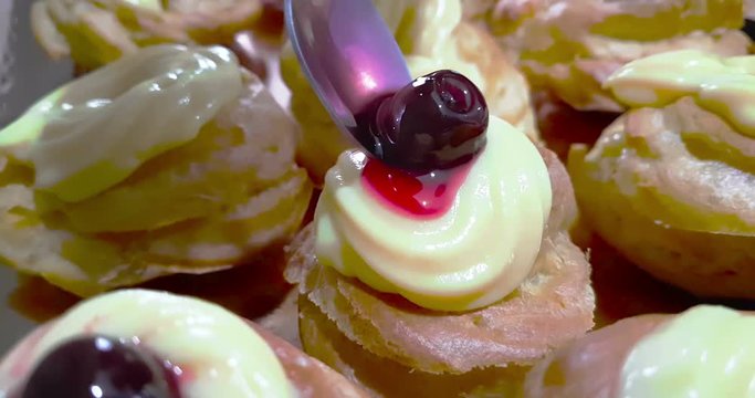 woman prepares delicious cream desserts called zeppole of St. Joseph and use the spoon for insert black cherry with syrup on top, italian traditional religious event,  party of daddy