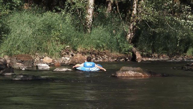 Model released person enjoying a hot summer's day at the river floating down on inner tube raft.