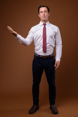 Fototapeta na wymiar Young handsome businessman against brown background