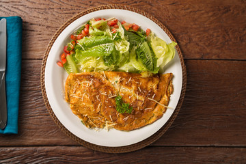omelette with cherry tomatoes and lettuce. and grated cheese, shot from above on a rustic wooden texture with a place for text. Top view
