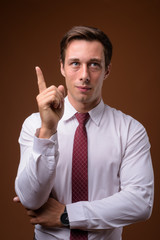 Young handsome businessman against brown background