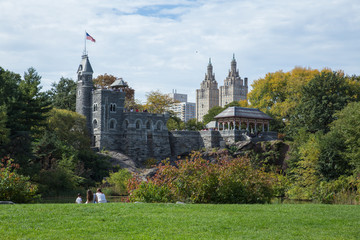 a family sitting on the lawn at the central park looking toward the Belvedere castle - obrazy, fototapety, plakaty
