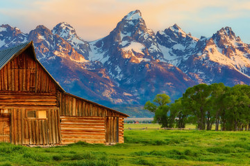 This abandoned, vintage barn in Mormon Row has the Grand Tetons in the background.  Located in Jackson Hole, Wyoming, it is listed on the National Register of Historic Places. - obrazy, fototapety, plakaty