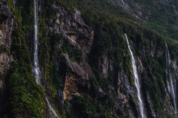 A stunning scene of nature with many waterfalls from the high mountain at Milford Sound, New Zealand.