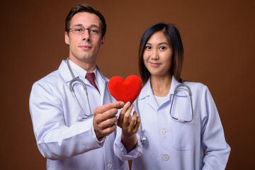 Studio shot of two young doctors together against brown backgrou
