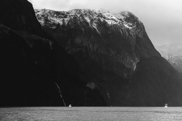 A stunning scene of nature with snow mountain and waterfalls at Milford Sound, New Zealand. Black and white photo.