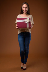 Studio shot of young beautiful woman against brown background