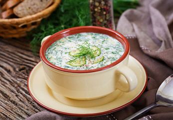 Summer yogurt cold soup with egg, cucumber, and dill on wooden table. Okroshka. Russian food
